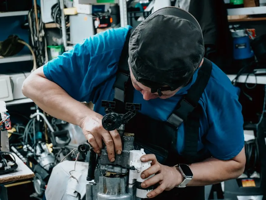 Focused technician working on machinery in a cluttered workshop, showcasing skilled labor.